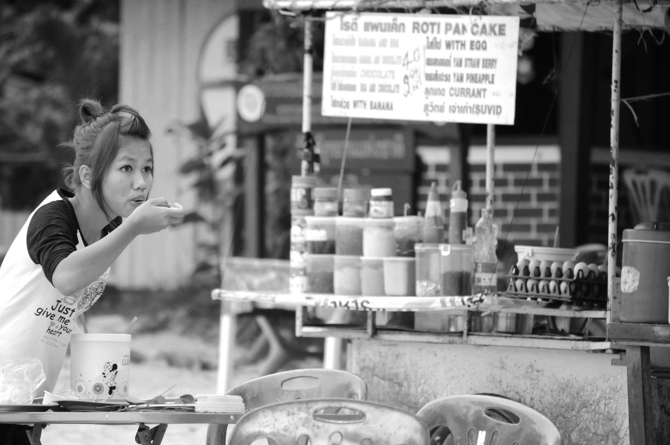 Girl on Koh Samet tasting food A girl on Koh Samet tasting food in front of a cart selling roti, Thai pancakes