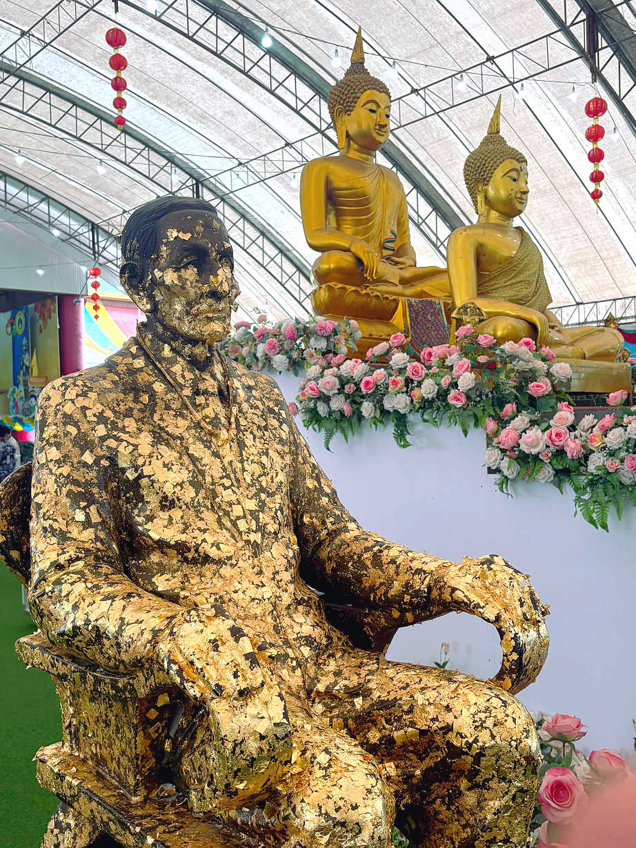 Visitors applying gold leaf to statues as an act of devotion